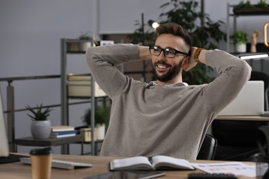 Photo of Happy man relaxing at workplace in office