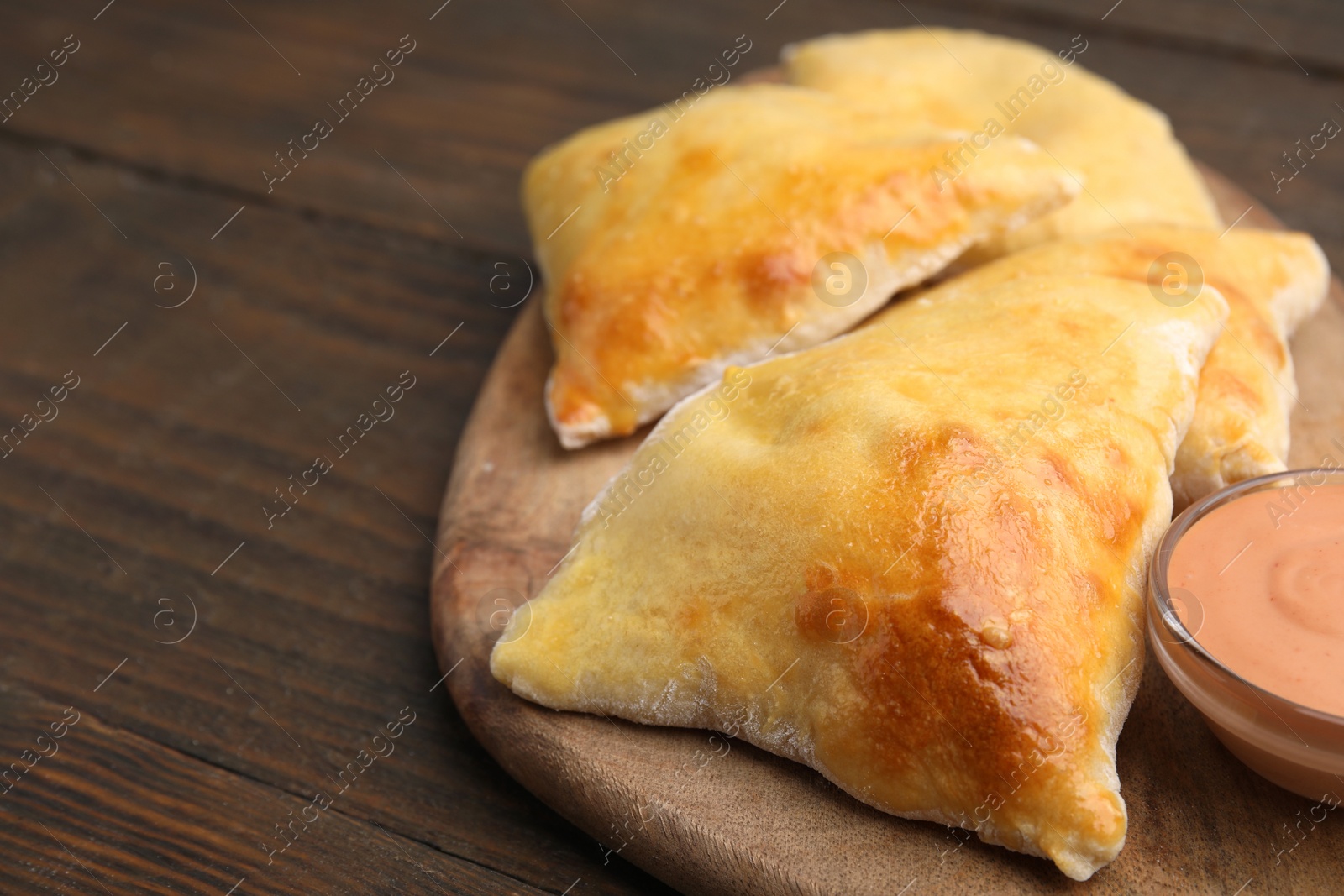 Photo of Delicious samosas and sauce on wooden table, closeup. Space for text