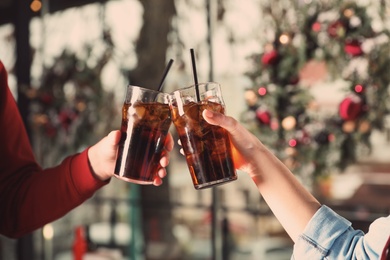 Young couple with glasses of cola indoors, closeup