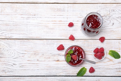 Flat lay composition with delicious raspberry jam on wooden background