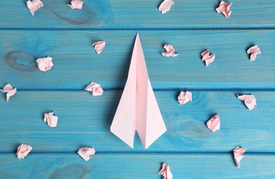 Flat lay composition with plane and many crumpled pieces of paper on light blue wooden table