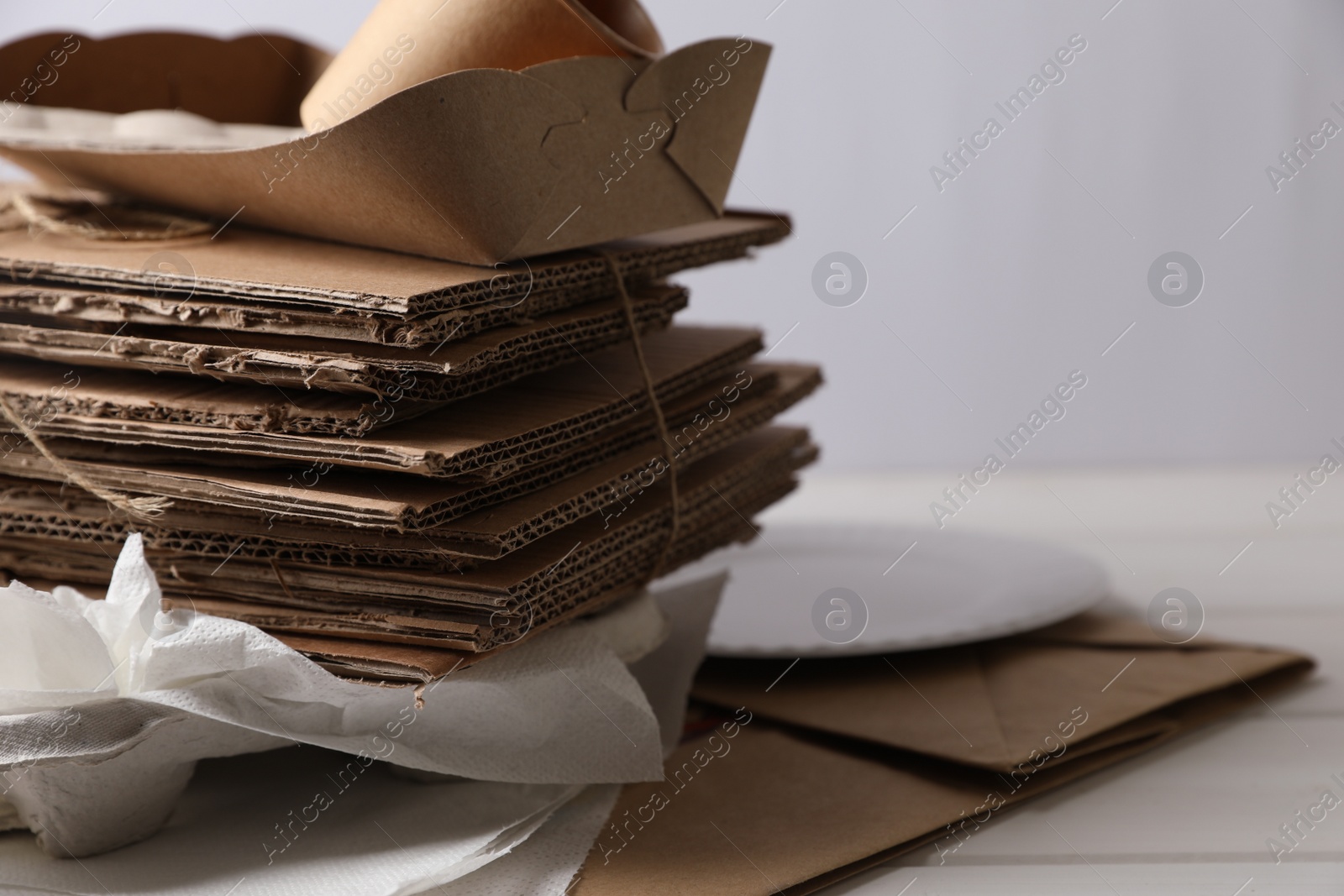 Photo of Heap of waste paper on white wooden table, closeup. Space for text