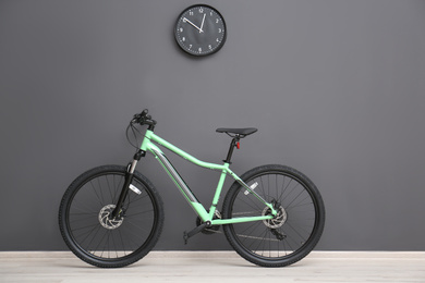 Photo of Modern green bicycle near grey wall indoors