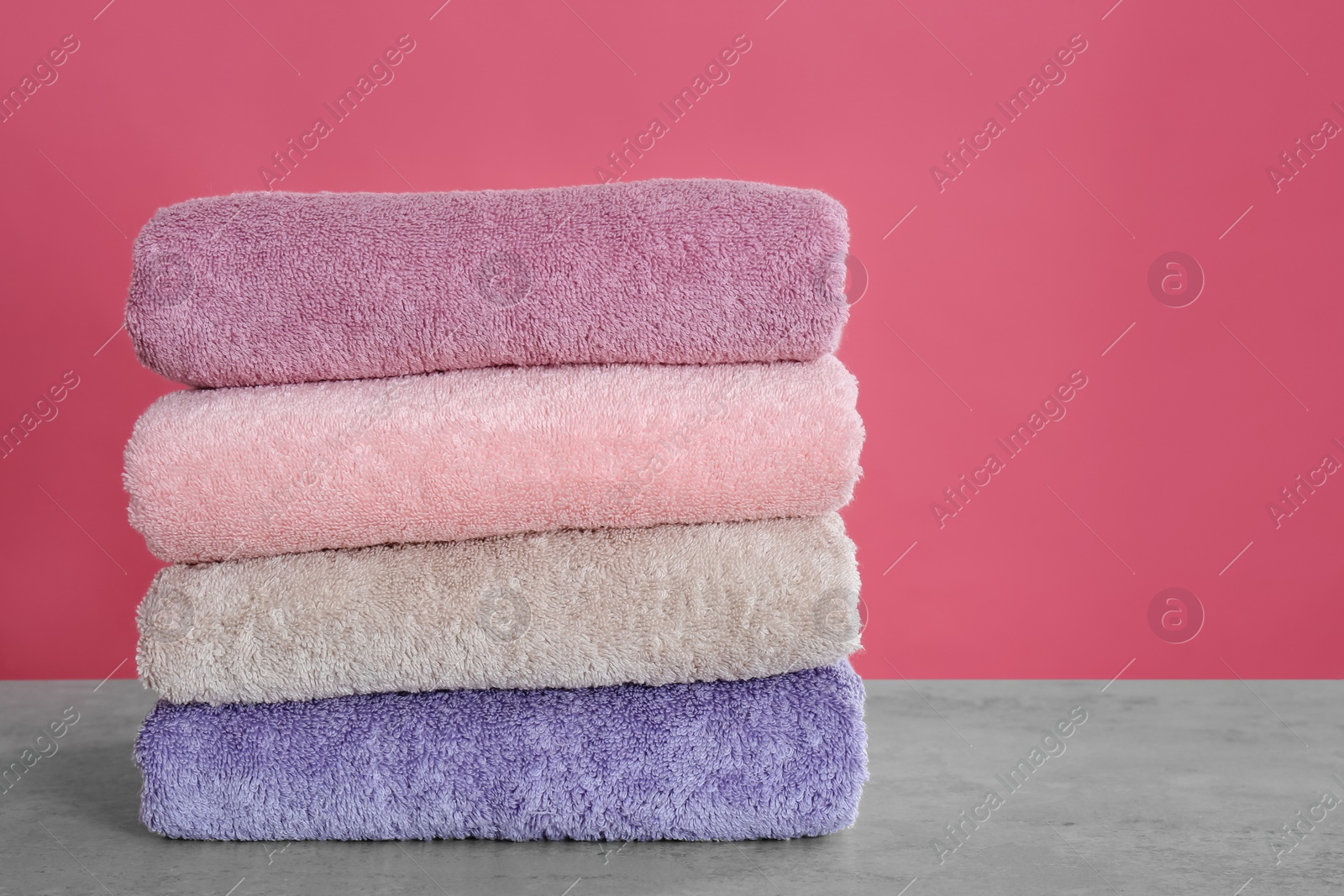 Photo of Stack of color towels on light grey stone table, closeup