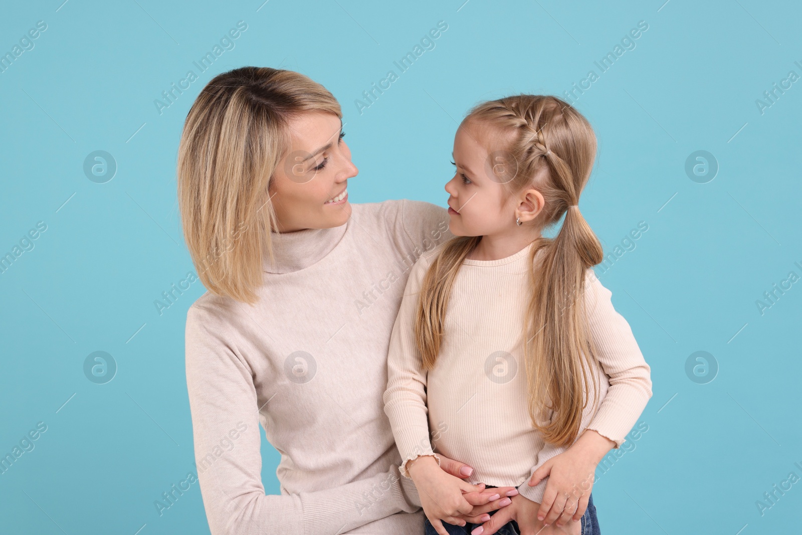 Photo of Happy mother and daughter on light blue background