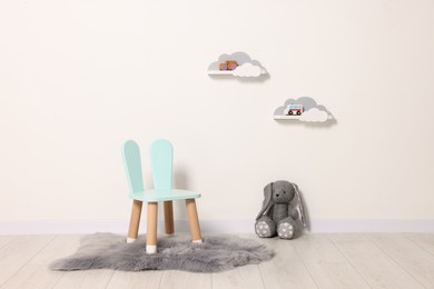 Photo of Beautiful children's room with light wall, chair and toys. Interior design
