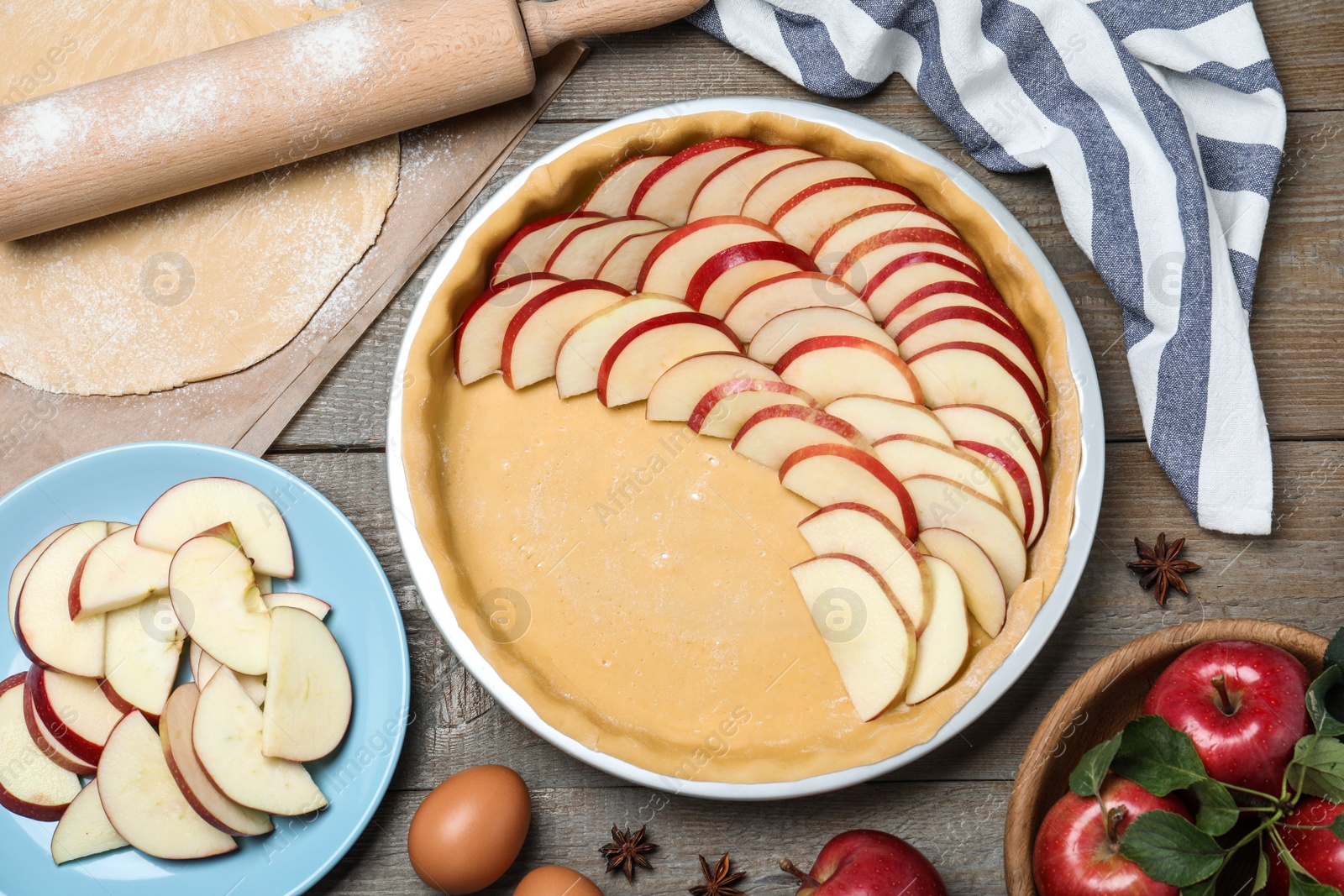 Photo of Dish with fresh apple slices and raw dough on wooden table, flat lay. Baking pie