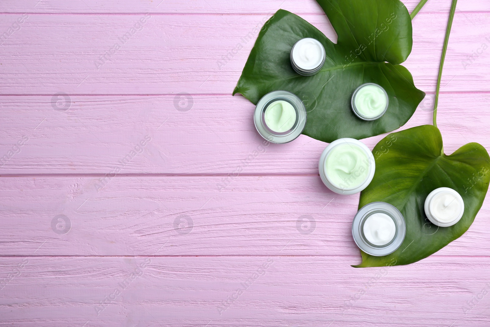 Photo of Jars with body cream on wooden background