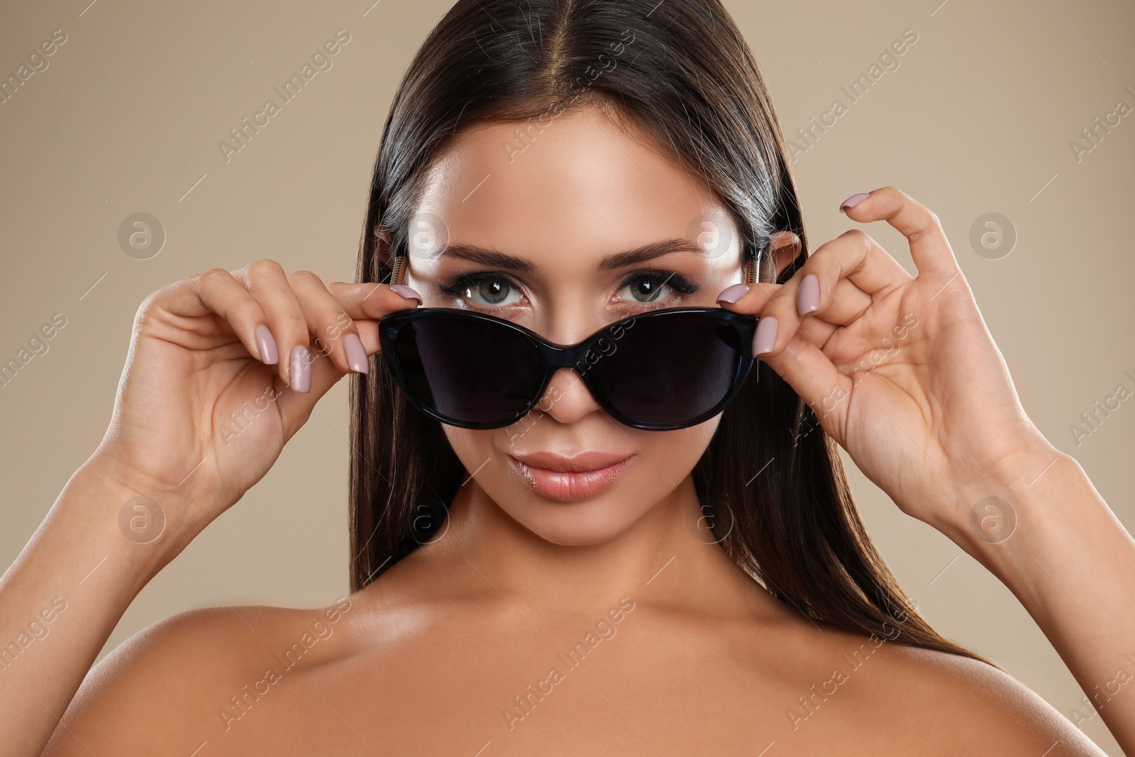 Photo of Beautiful young woman wearing sunglasses on beige background