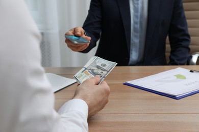 Photo of Businessman putting money on card at desk in bank, closeup