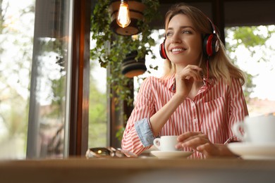 Young woman with headphones listening to music in cafe