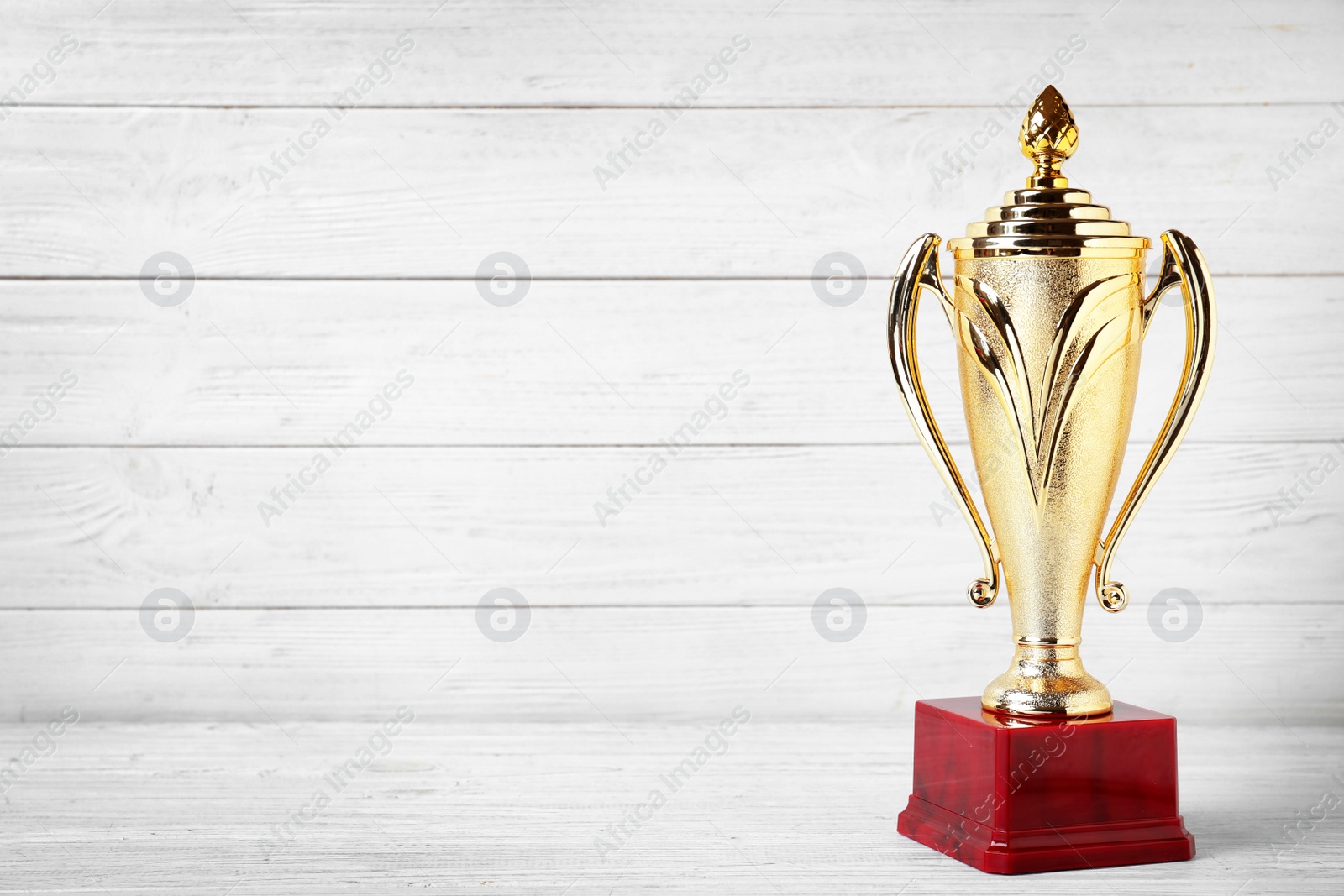 Photo of Golden trophy cup on white wooden background. Space for text