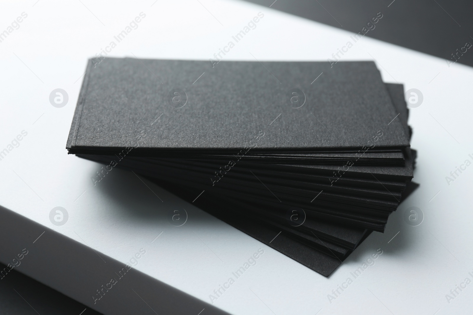 Photo of Blank black business cards on white background, closeup