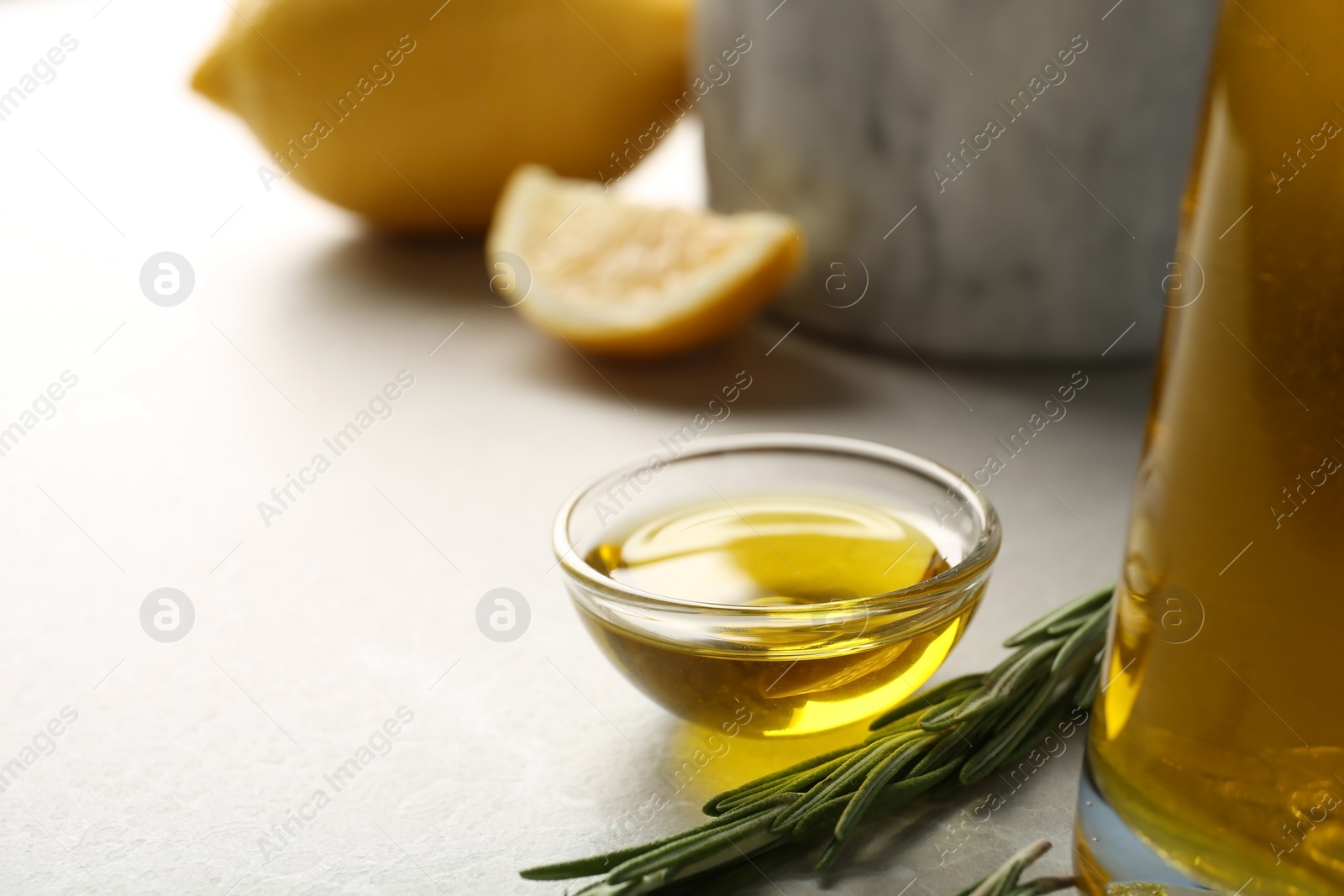 Photo of Small bowl of rosemary oil on table