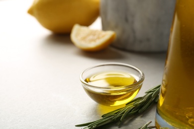 Photo of Small bowl of rosemary oil on table