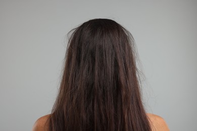 Photo of Woman with damaged messy hair on grey background, back view