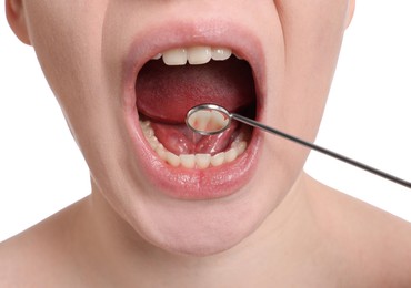 Examining young woman's teeth and gums with mirror on white background, closeup