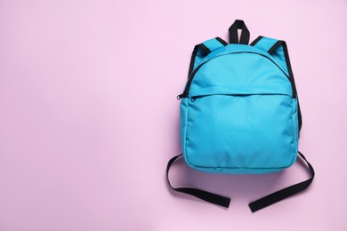 Photo of Stylish light blue backpack on violet background, top view. Space for text