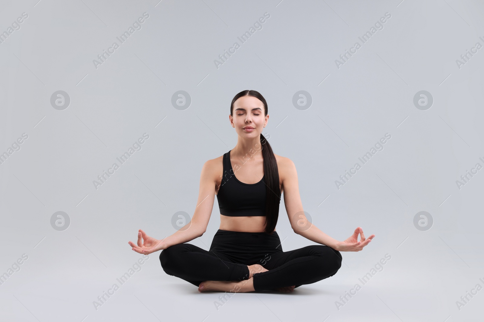 Photo of Beautiful young woman practicing yoga on grey background. Lotus pose