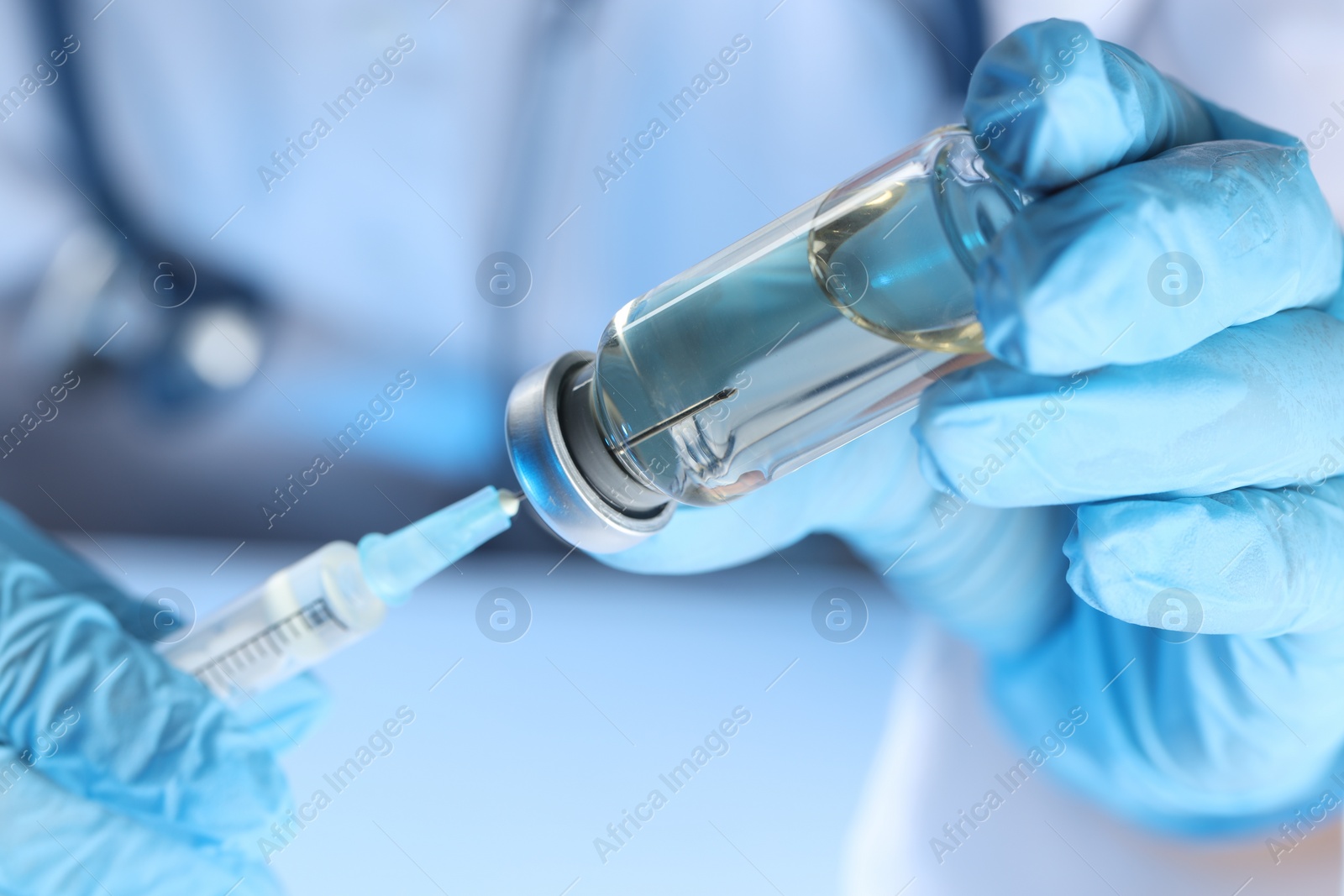 Photo of Doctor filling syringe with medication from glass vial, closeup