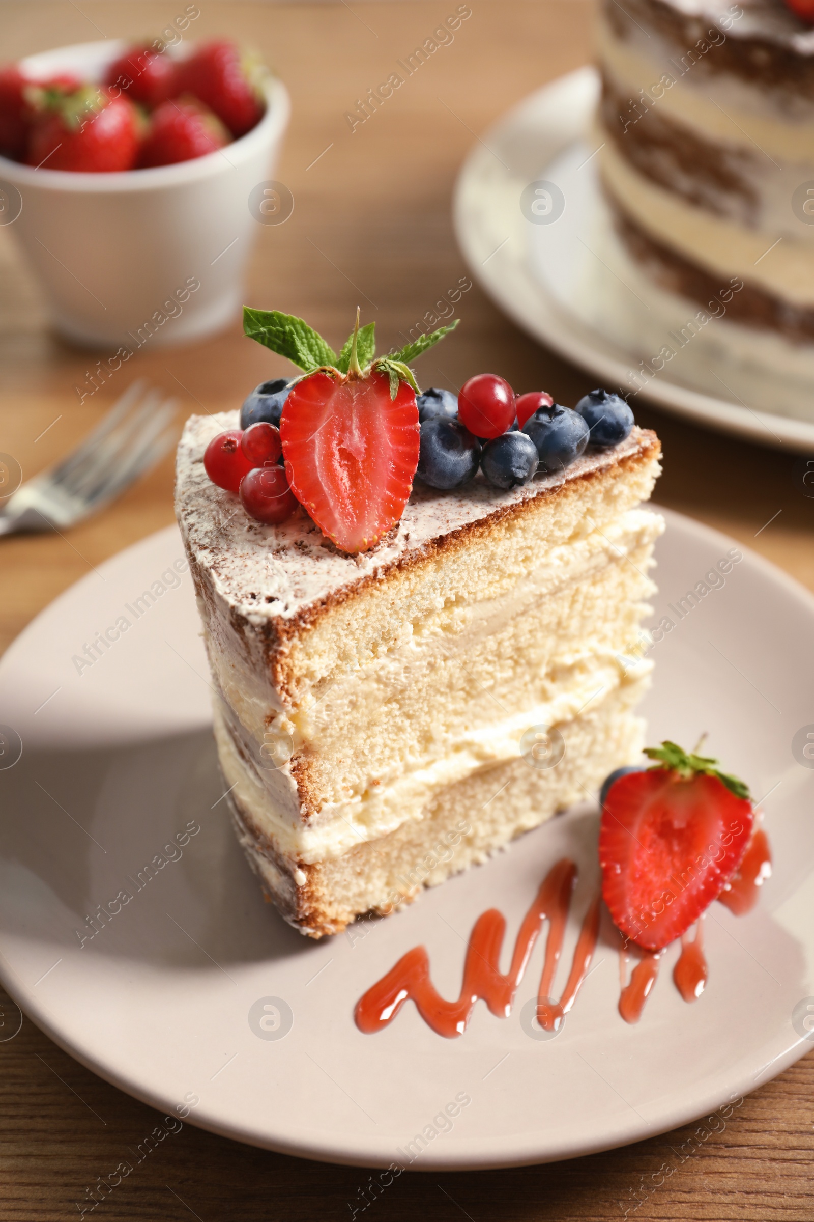 Photo of Piece of delicious homemade cake with fresh berries served on wooden table