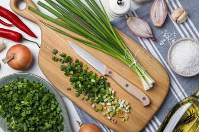 Photo of Chopped green spring onion, stems and other ingredients on white table, flat lay