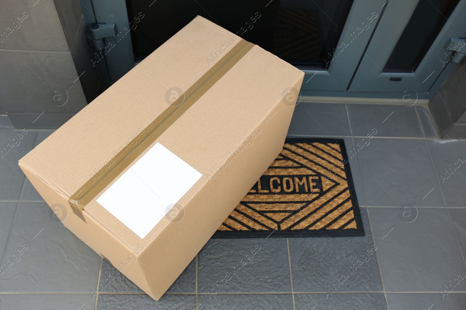 Photo of Cardboard box near door, above view. Parcel delivery service