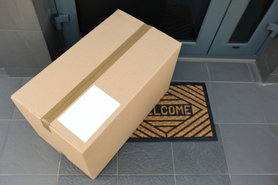Photo of Cardboard box near door, above view. Parcel delivery service