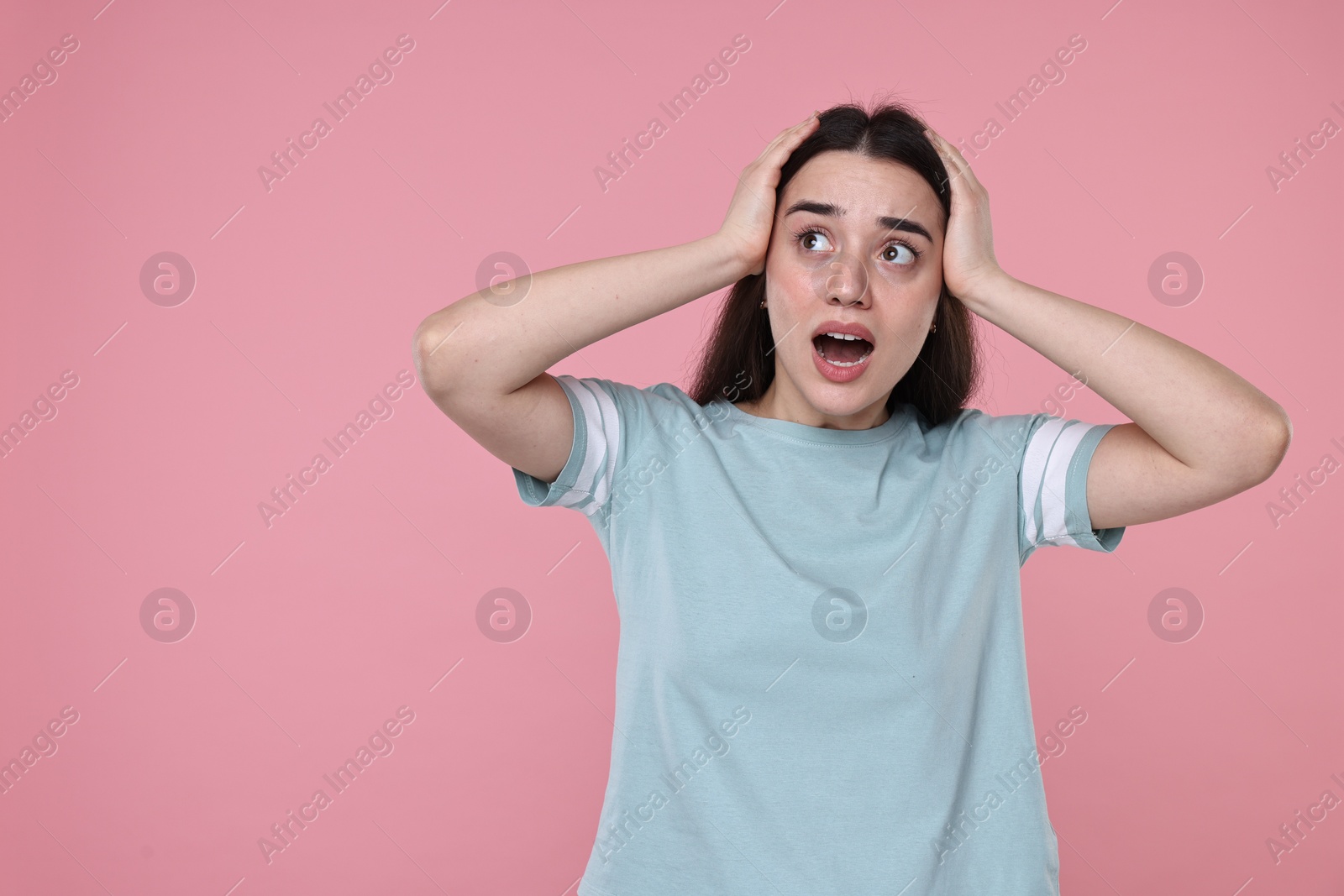 Photo of Portrait of surprised woman on pink background. Space for text