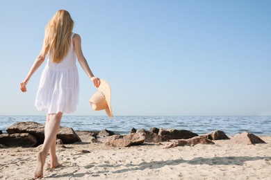 Young woman walking near sea on sunny day in summer, back view
