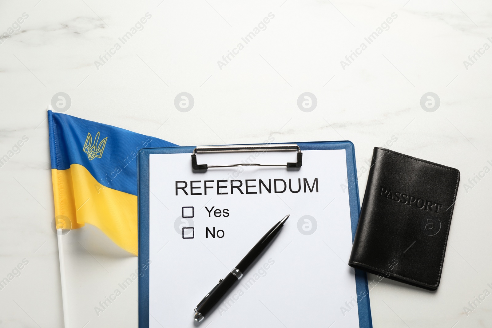 Photo of Referendum ballot with passport, pen and flag of Ukraine on white marble table, flat lay