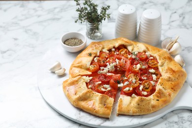 Photo of Tasty galette with tomato, thyme and cheese (Caprese galette) on white marble table, closeup. Space for text