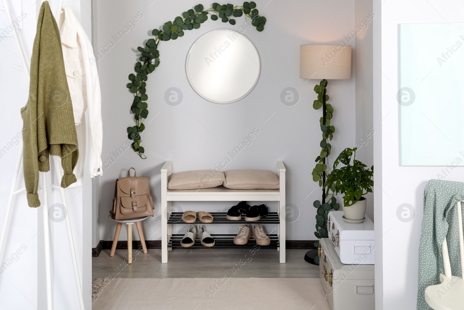 Photo of Hallway interior with stylish furniture and round mirror on light wall