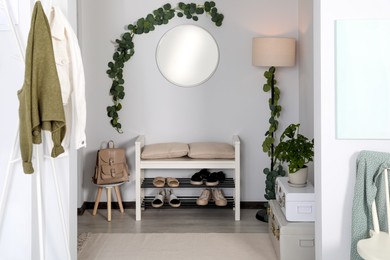 Hallway interior with stylish furniture and round mirror on light wall