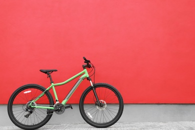 Photo of New modern color bicycle near red wall outdoors