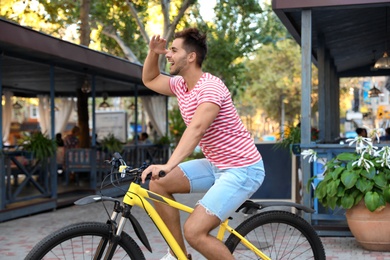 Handsome young man riding bicycle on city street