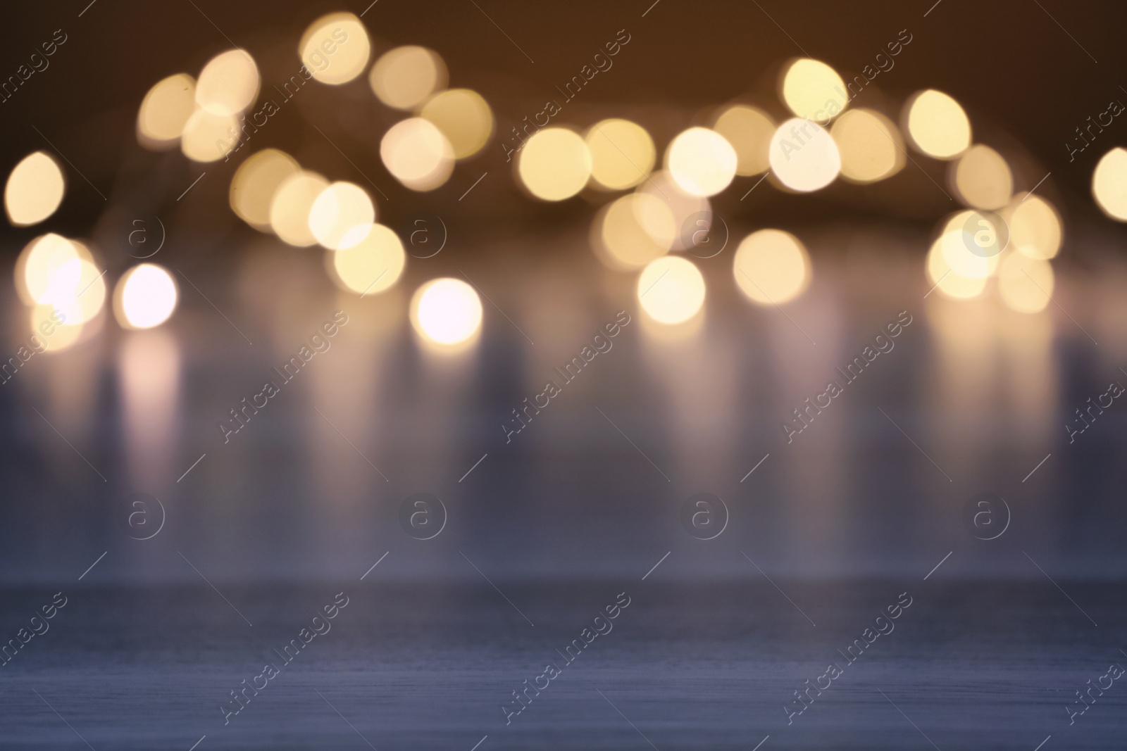 Photo of Blurred view of beautiful lights on wooden table, space for text