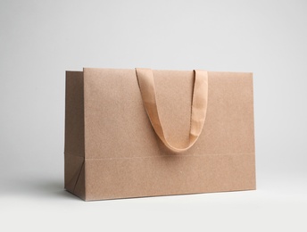 Paper shopping bag with comfortable handles on white background. Mockup for design