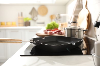Photo of Frying pan with cooking oil on cooktop in kitchen