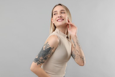 Portrait of beautiful tattooed woman on gray background