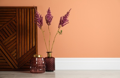 Stylish decorative vases on floor near wall