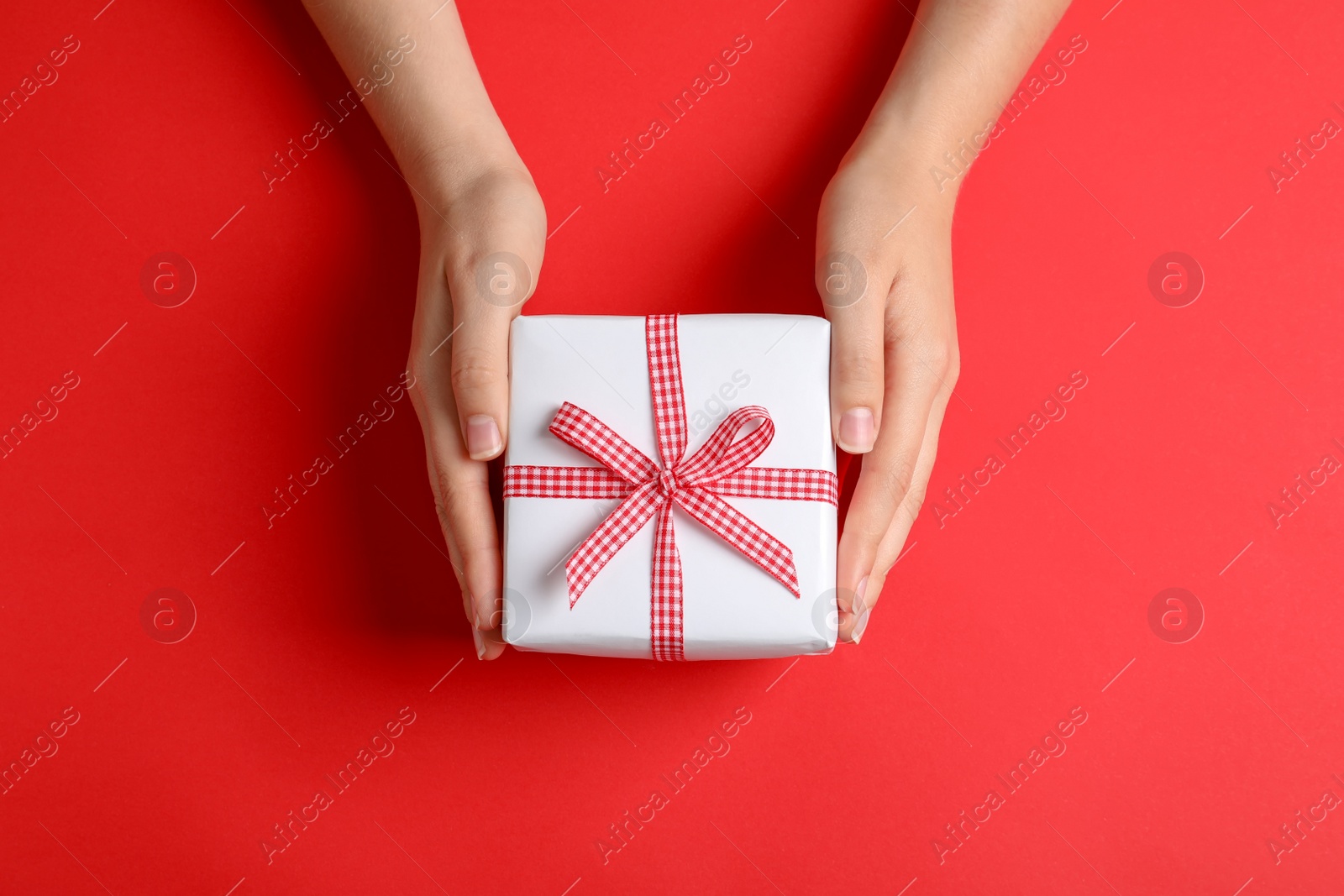 Photo of Woman holding gift box on color background, top view