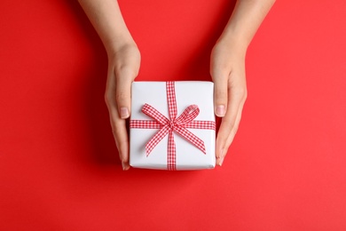 Photo of Woman holding gift box on color background, top view