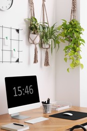 Cozy workplace with computer, modern furniture and houseplants at home