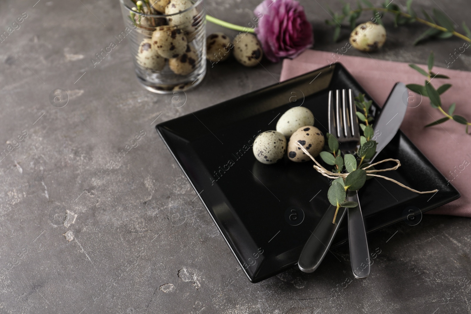 Photo of Festive Easter table setting with quail eggs and floral decoration on dark background