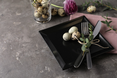 Festive Easter table setting with quail eggs and floral decoration on dark background