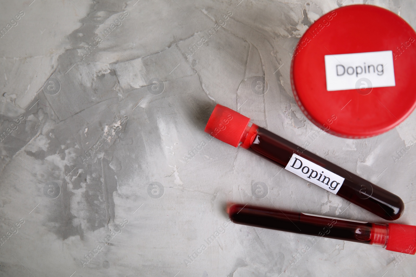Photo of Jar of urine and blood samples with words Doping on light grey stone table, flat lay. Space for text
