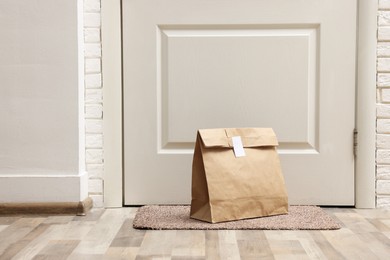 Paper bag on door mat near entrance indoors