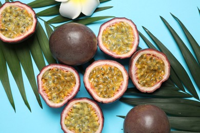 Passion fruits (maracuyas), flower and palm leaves on light blue background, flat lay