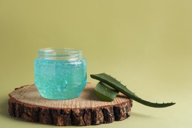 Photo of Jar of blue cosmetic gel and aloe on green background. Space for text